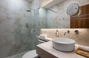 Une salle de bain moderne avec une douche carrelée en marbre, un lavabo rond et un meuble-lavabo en bois.