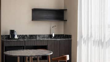 Una cocina moderna con una mesa redonda y dos sillas, un lavamanos integrado y un estante de madera oscura sobre la encimera.