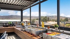 Un espace buffet proposant une variété de plats, un coin salon et une vue sur le paysage grâce à de grandes fenêtres.