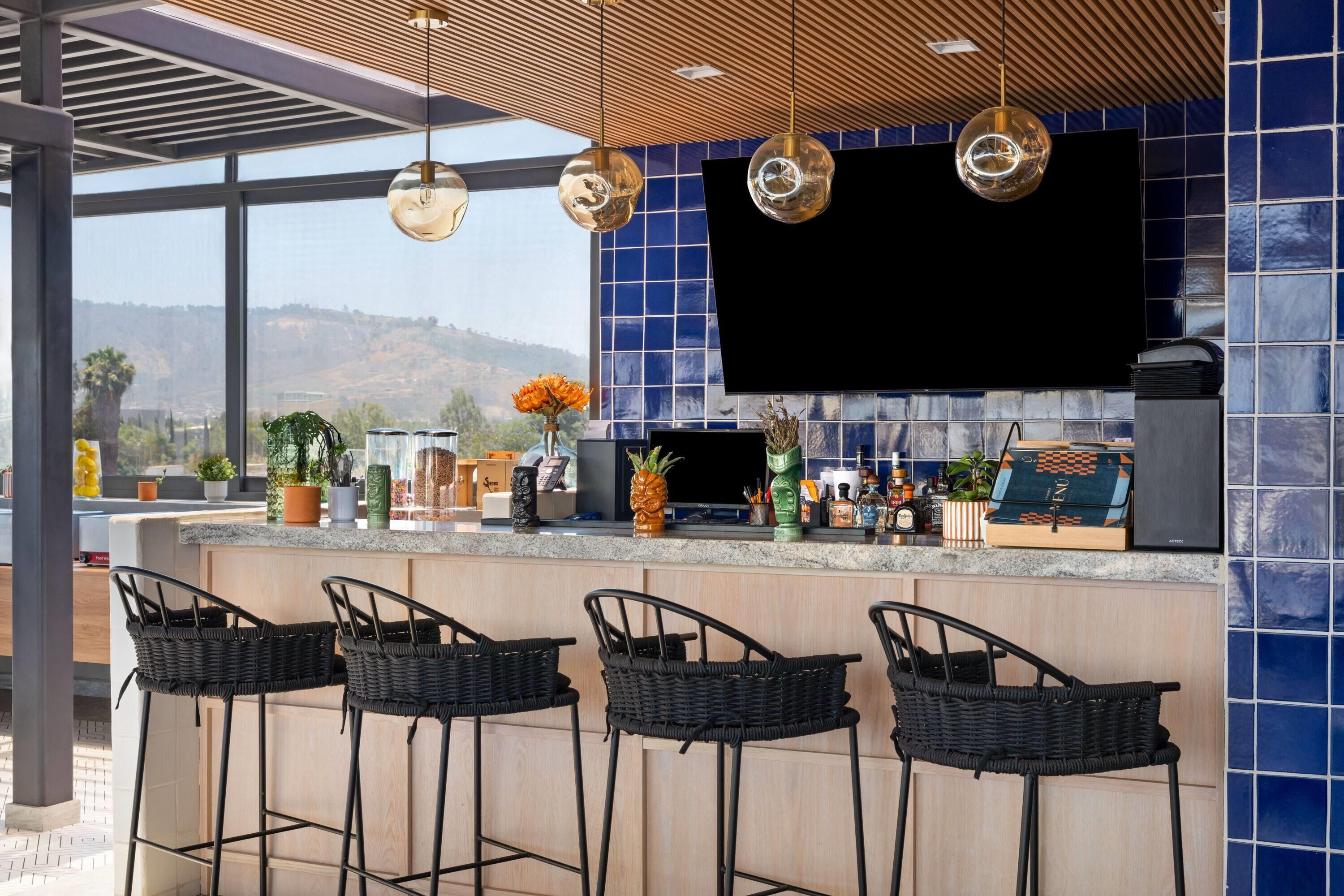 Una cocina moderna con un televisor grande, taburetes de bar y una vista panorámica.
