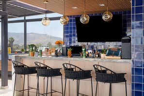 Una cocina moderna con un televisor grande, taburetes de bar y una vista panorámica.