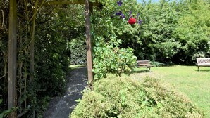 A garden pathway with a wooden bench and a pergola with climbing plants. - Ferienhaus in Rerik in Ostseenähe (Rerik)