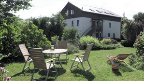 A house with a large garden, outdoor seating, and a car parked in the driveway. - Ferienhaus in Rerik in Ostseenähe (Rerik)