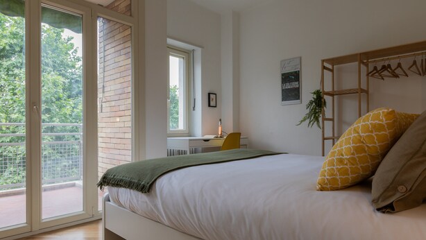 A bedroom with a bed, a desk, and a window. - Casa Cinema by Wonderful Italy (Turin)