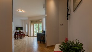 A hallway with wooden flooring, a dining area with chairs and a table, and a potted plant. - Casa Cinema by Wonderful Italy (Turin)
