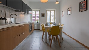 A modern kitchen with wooden cabinets, a dining table with yellow chairs, and pendant lighting. - Casa Cinema by Wonderful Italy (Turin)