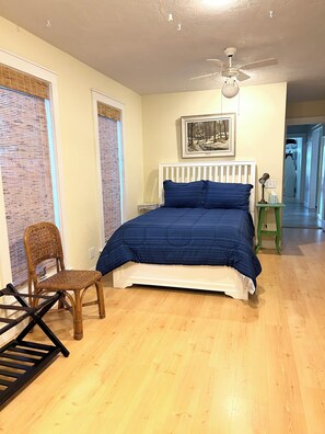 A bedroom with a bed, a chair, a ceiling fan, and a painting on the wall. - Spacious Home with Water Views (Cedar Key)