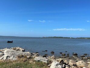 A rocky shoreline with calm water and a distant landmass. - Spacious Home with Water Views (Cedar Key)