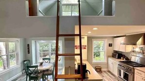 Une cuisine spacieuse avec un coin repas en mezzanine, un plancher en bois et un îlot central.