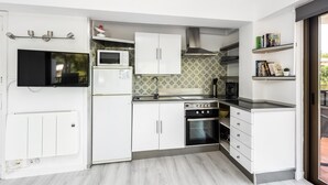Una cocina moderna con armarios blancos, microondas integrado, campana extractora de acero inoxidable y estufa a gas.