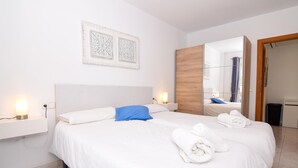 Habitación de hotel con una cama grande, lámparas de noche, un panel de pared de madera y un espejo que refleja el baño.