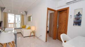 Una sala de estar moderna con un sofá blanco, una mesa de centro de cristal y un comedor con sillas blancas.