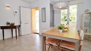 A dining area with a wooden table, chairs, a hanging light fixture, and a view of the outdoors through a window. - CA NA MARONA - Dúplex al centre del poble (Colonia de Sant Pere)