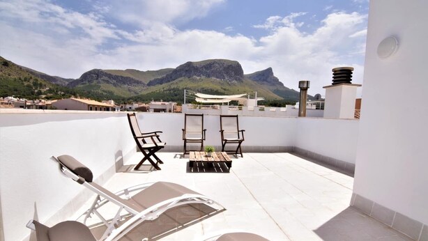 A rooftop terrace with a table and chairs, a sun lounger, and a view of mountains. - CA NA MARONA - Dúplex al centre del poble (Colonia de Sant Pere)