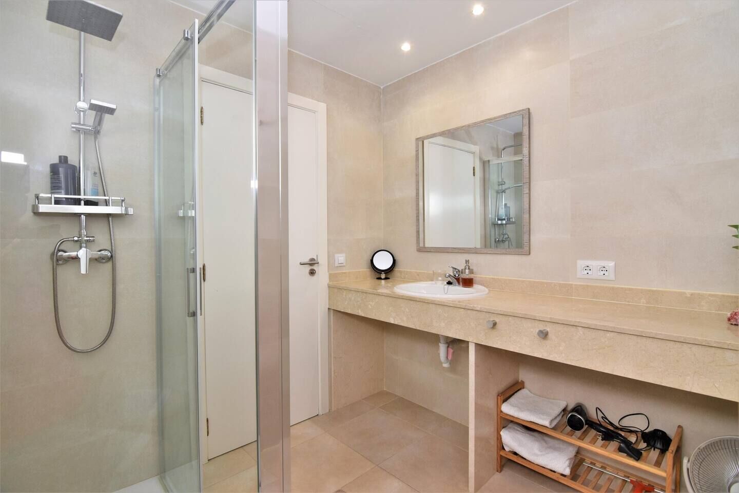 Un baño moderno con ducha de vidrio, un lavamanos con espejo y un perchero para toallas.