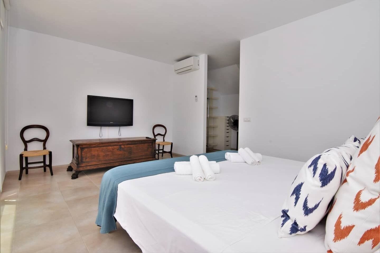 Une chambre d’hôtel avec un lit, une télévision, une commode en bois et une chaise.