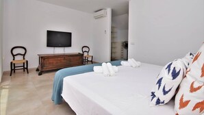 A hotel room with a bed, a TV, a wooden dresser, and a chair. - CA NA MARONA - Dúplex al centre del poble (Colonia de Sant Pere)