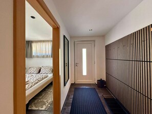 A narrow hallway with a bed on the left, a door at the end, and a wall with vertical slats on the right. - Apartment in Untertauern near Obertauern Skiing (Untertauern)