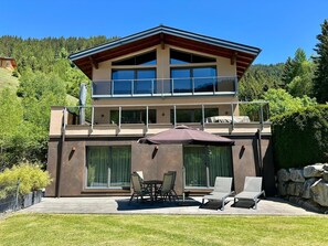 A modern two-story house with a balcony, large windows, and outdoor seating. - Apartment in Untertauern near Obertauern Skiing (Untertauern)