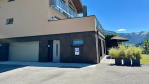 Ein zweistöckiges Gebäude mit Garage, Parkschild und Blick auf Berge.