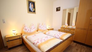 Un dormitorio con cama de madera, dos mesitas de noche, un tocador, un espejo y un armario.