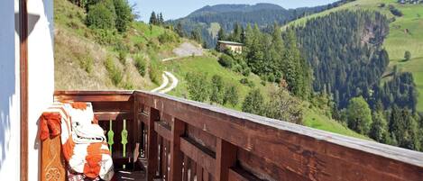 Un balcón de madera con vistas a un camino sinuoso a través de un paisaje montañoso.