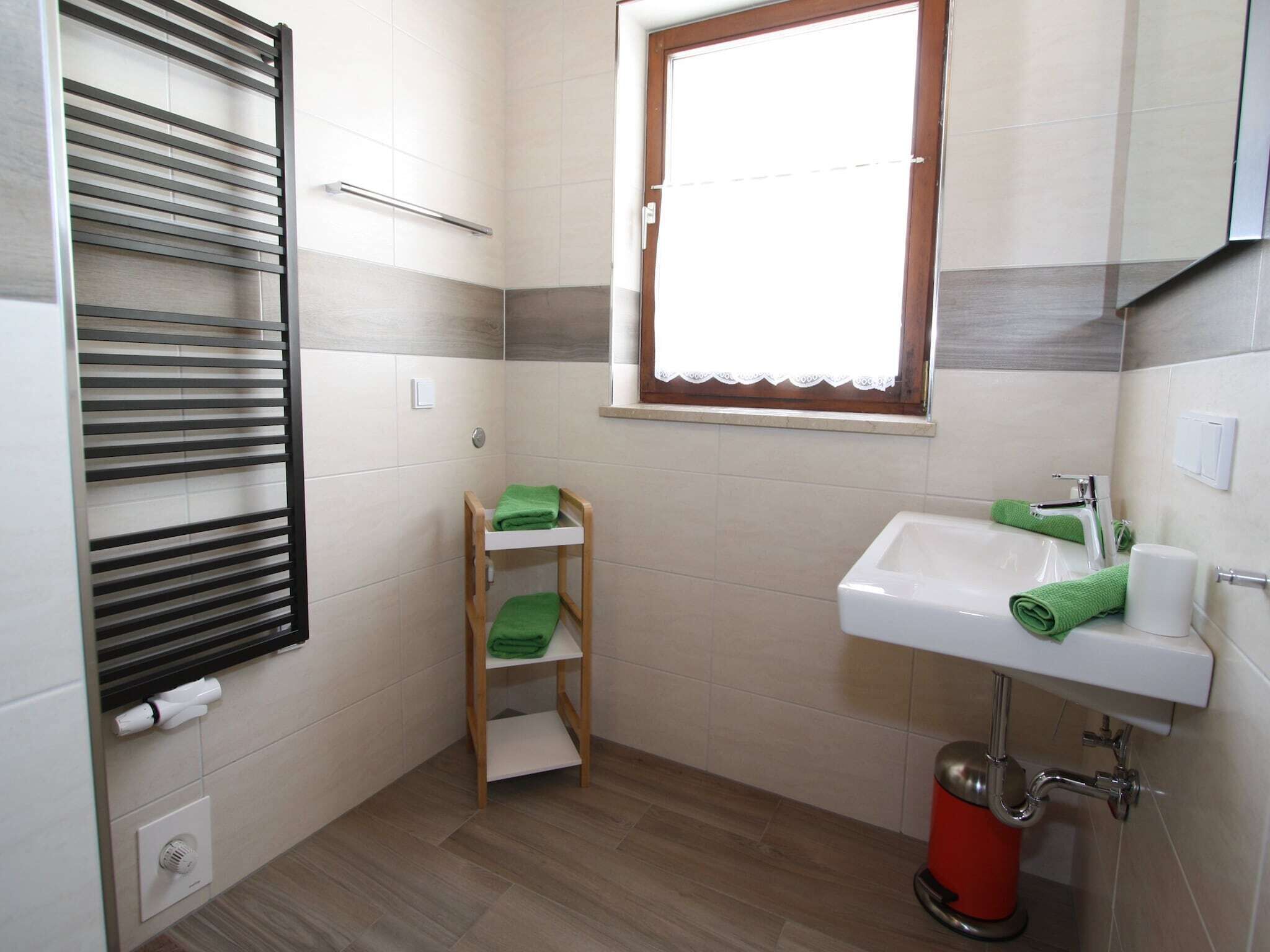 Un baño con ducha, lavamanos y ventana.