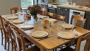 A modern kitchen with a dining table set for six, equipped with a microwave, oven, and a large window providing natural light. - to get together with family or friends and discover Normandy (Feuguerolles-Bully)