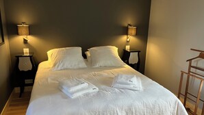A neatly made bed with white linens and towels, two bedside tables with lamps, and a wooden floor. - to get together with family or friends and discover Normandy (Feuguerolles-Bully)