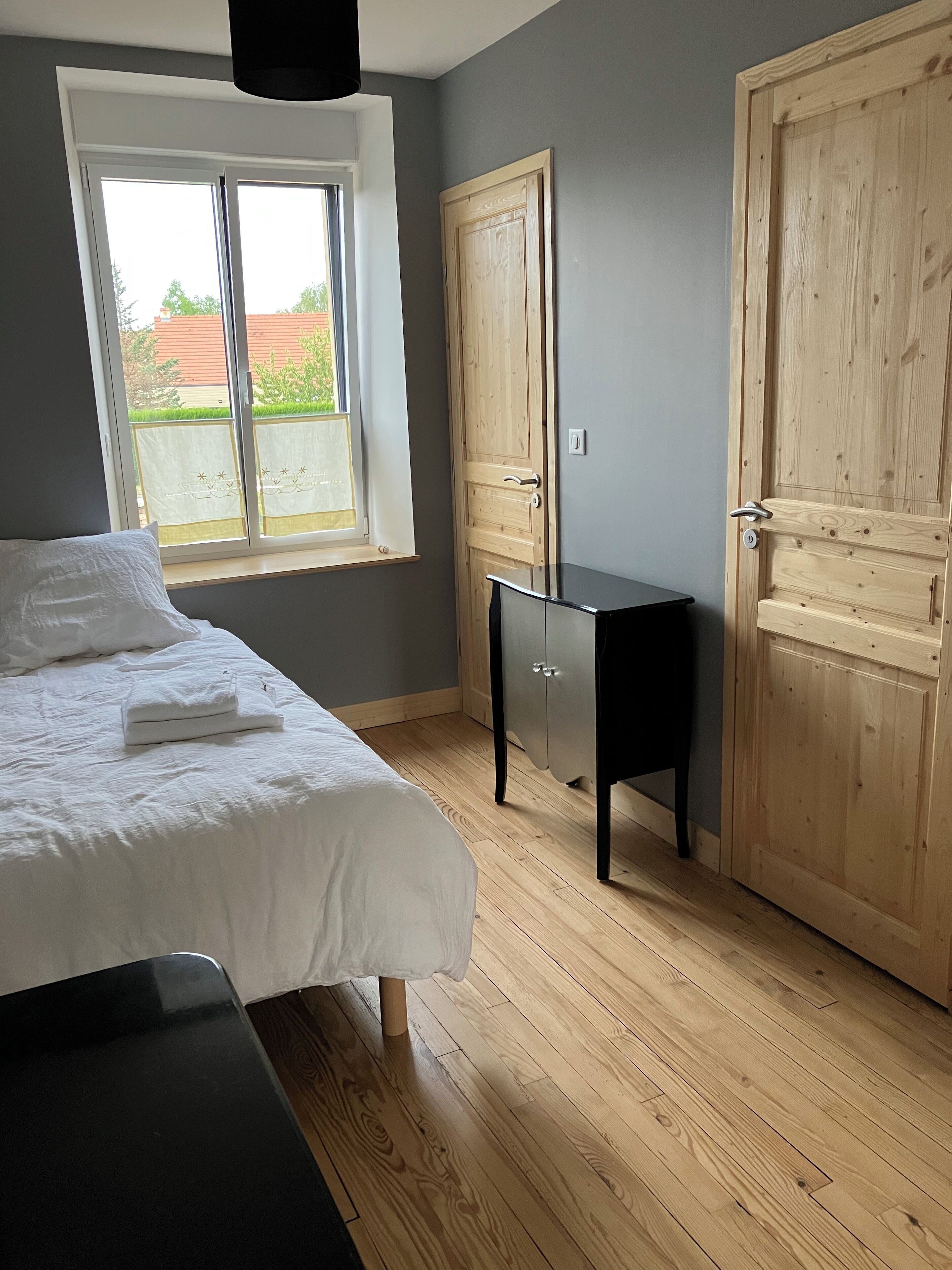 A bedroom with a bed, a window, a wardrobe, and a desk.