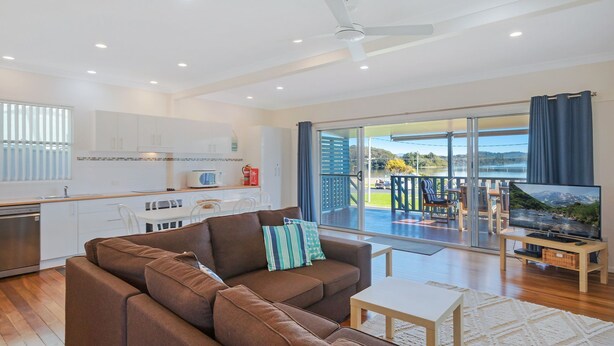 A modern living room with a brown sofa, a small white table, and a TV on a wooden stand.