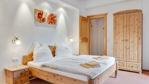 A bedroom with a wooden bed, bedside tables, a wardrobe, and a painting on the wall.
