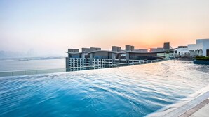 A modern infinity pool with a view of the city skyline at sunset.