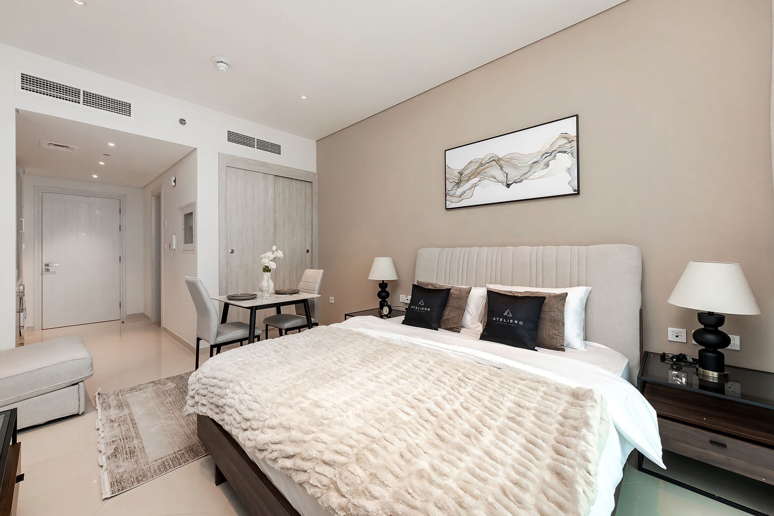 Un dormitorio moderno con una cama grande, mesitas de noche, un escritorio y una silla.