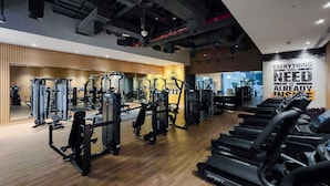 A gym with various exercise equipment, including treadmills and weight machines, and motivational wall art.