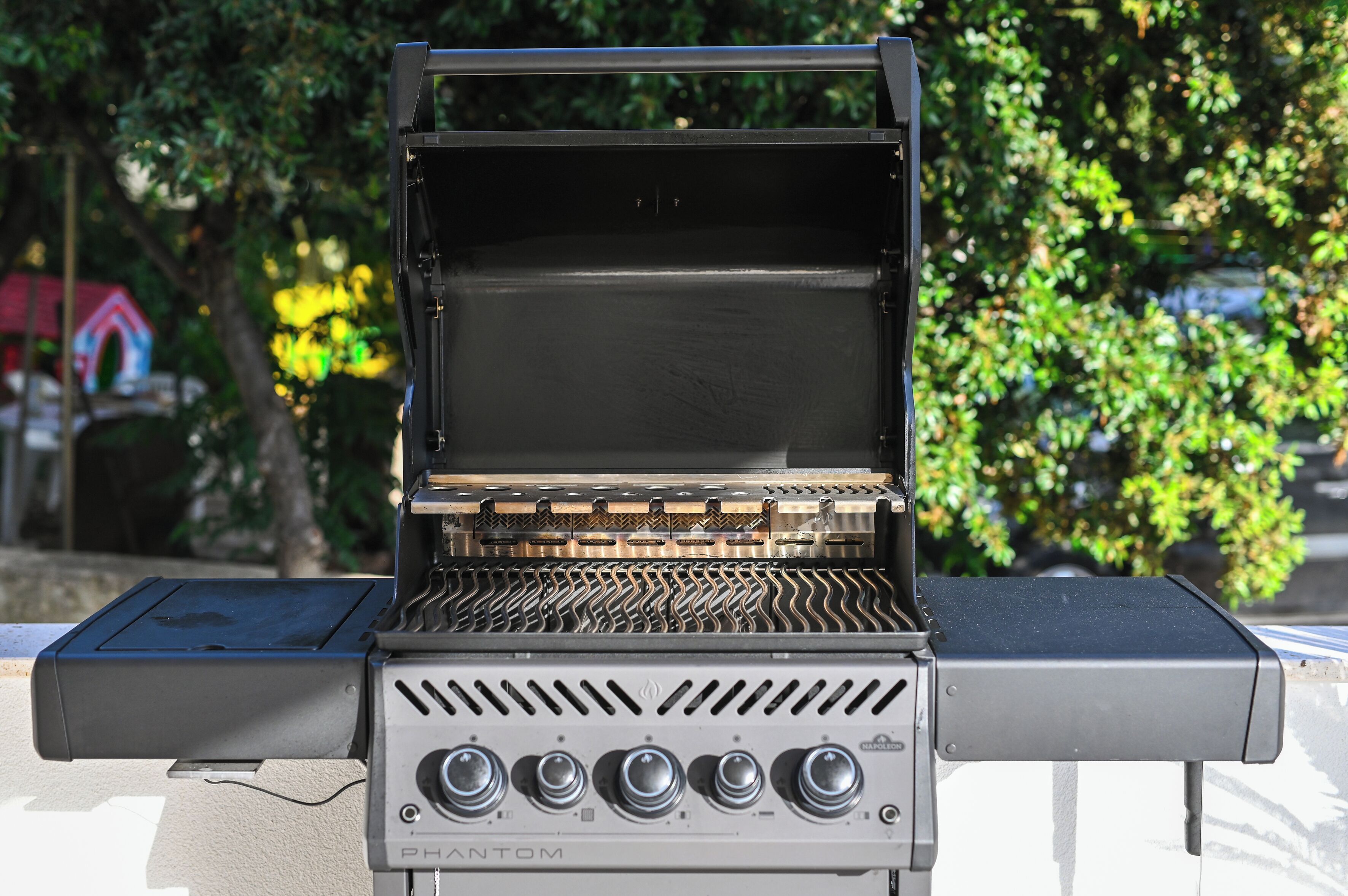 Ein PHANTOM tragbarer Grill mit Grilldeckel und Bedienelementen, draußen aufgestellt.