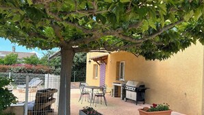 Un patio exterior con una parrilla, zona de estar y plantas en macetas.