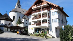 A multi-story building with a church steeple, a pharmacy, and a sign indicating a parking area. - Apartment in Leogang near Ski Slopes (Leogang)