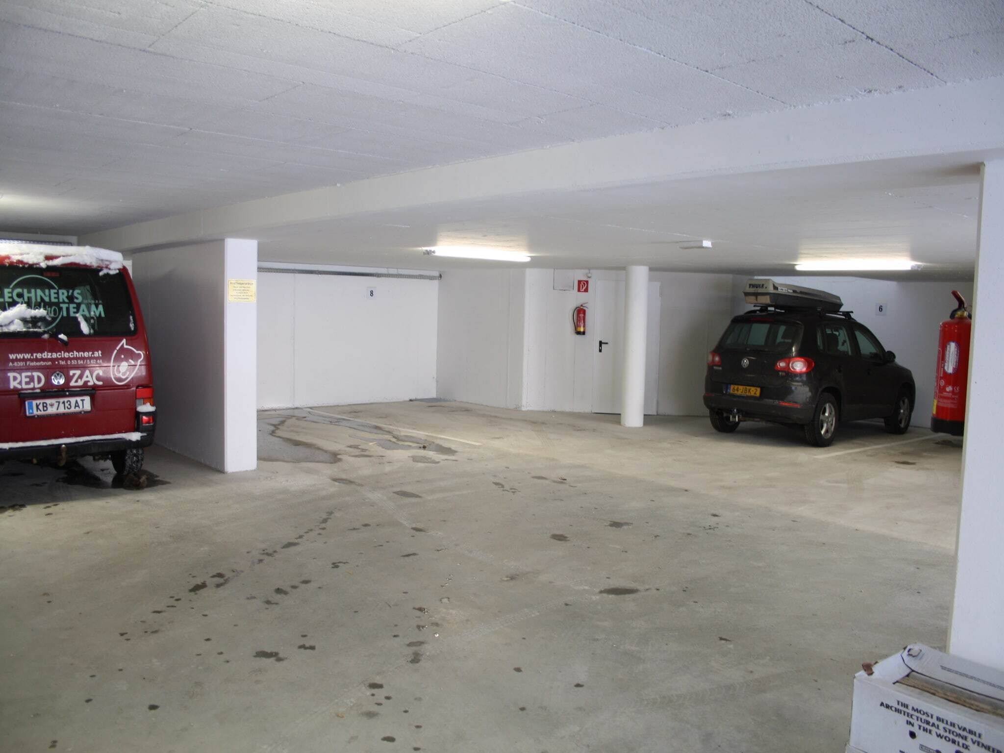 A parking garage with a red van and a black SUV.