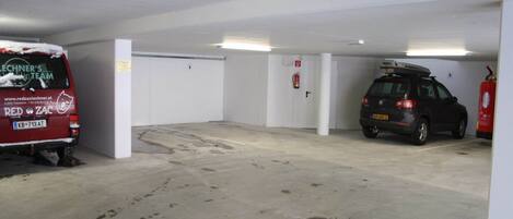 A parking garage with a red van and a black SUV.