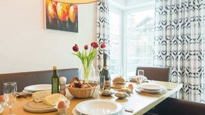 A dining table set with plates, glasses, a bottle of champagne, a basket of pretzels, a vase of tulips, and a bottle of olive oil. - Apartment in Leogang near Ski Slopes (Leogang)
