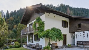 A two-story house with a balcony, a gravel driveway, and a garden with various plants and a bench. - Chalet in Leogang near Ski Lifts (Leogang)