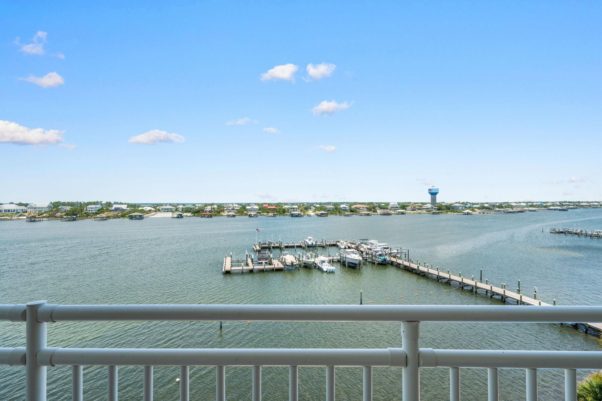 A marina with docked boats, a pier extending into the water, and a distant tower.