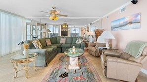 Tilava olohuone, jossa on kulmasohva, lasinen sohvapöytä ja koristeellinen matto.