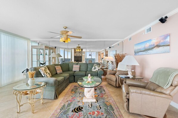 A spacious living room with a sectional sofa, a glass coffee table, and a decorative rug. - Seaspray Riverside 611 (Pensacola)