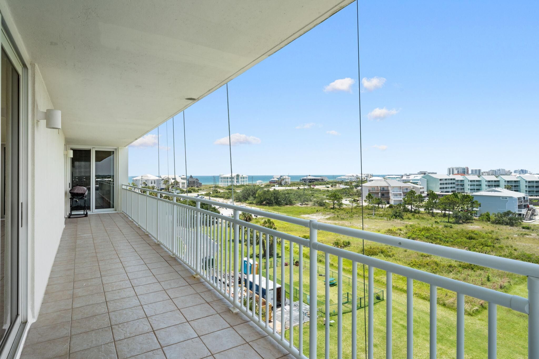 A balcony with a view of a coastal area, including buildings and greenery.