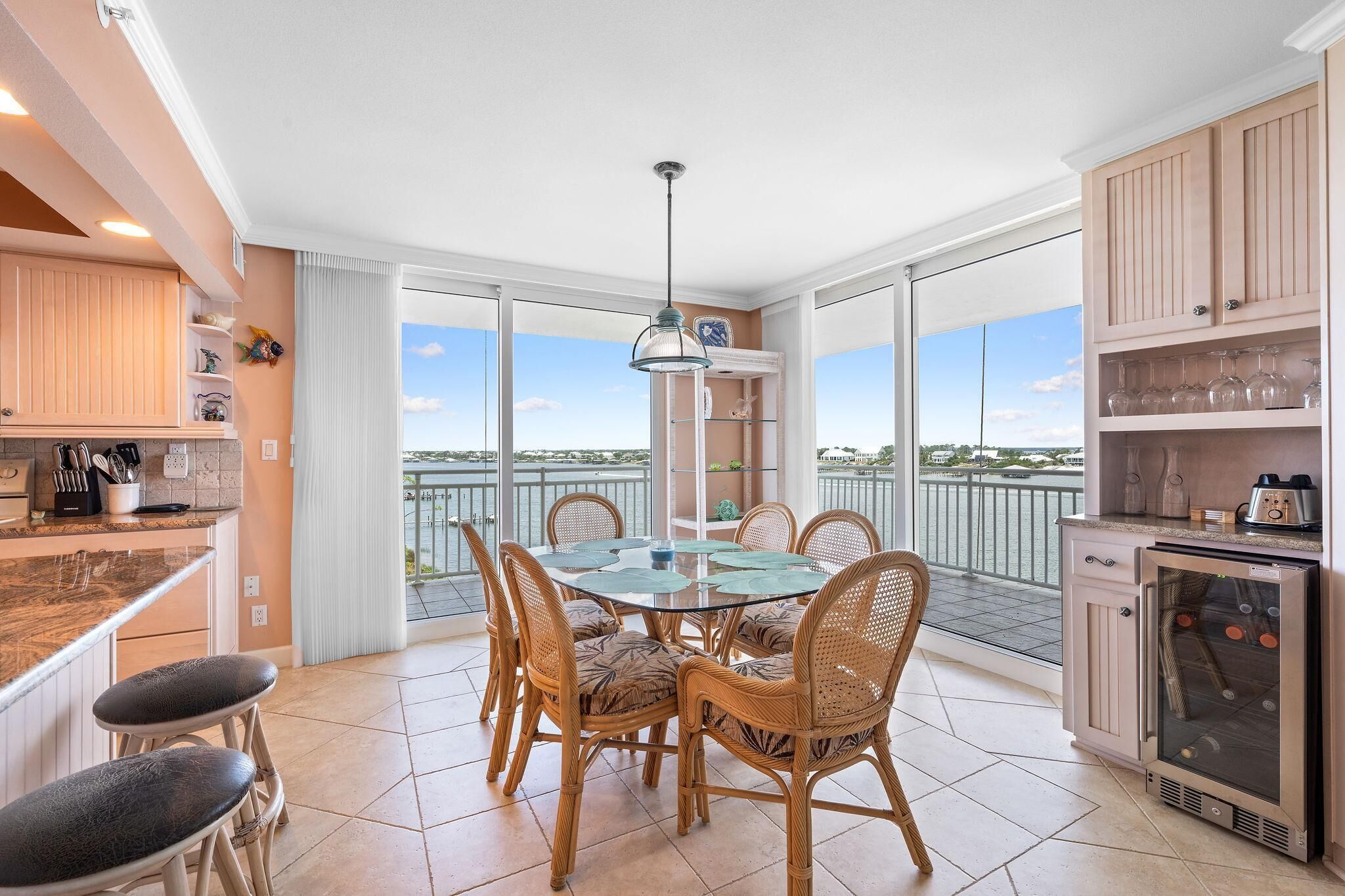 A kitchen with a dining area, large windows, and a view of the sea.
