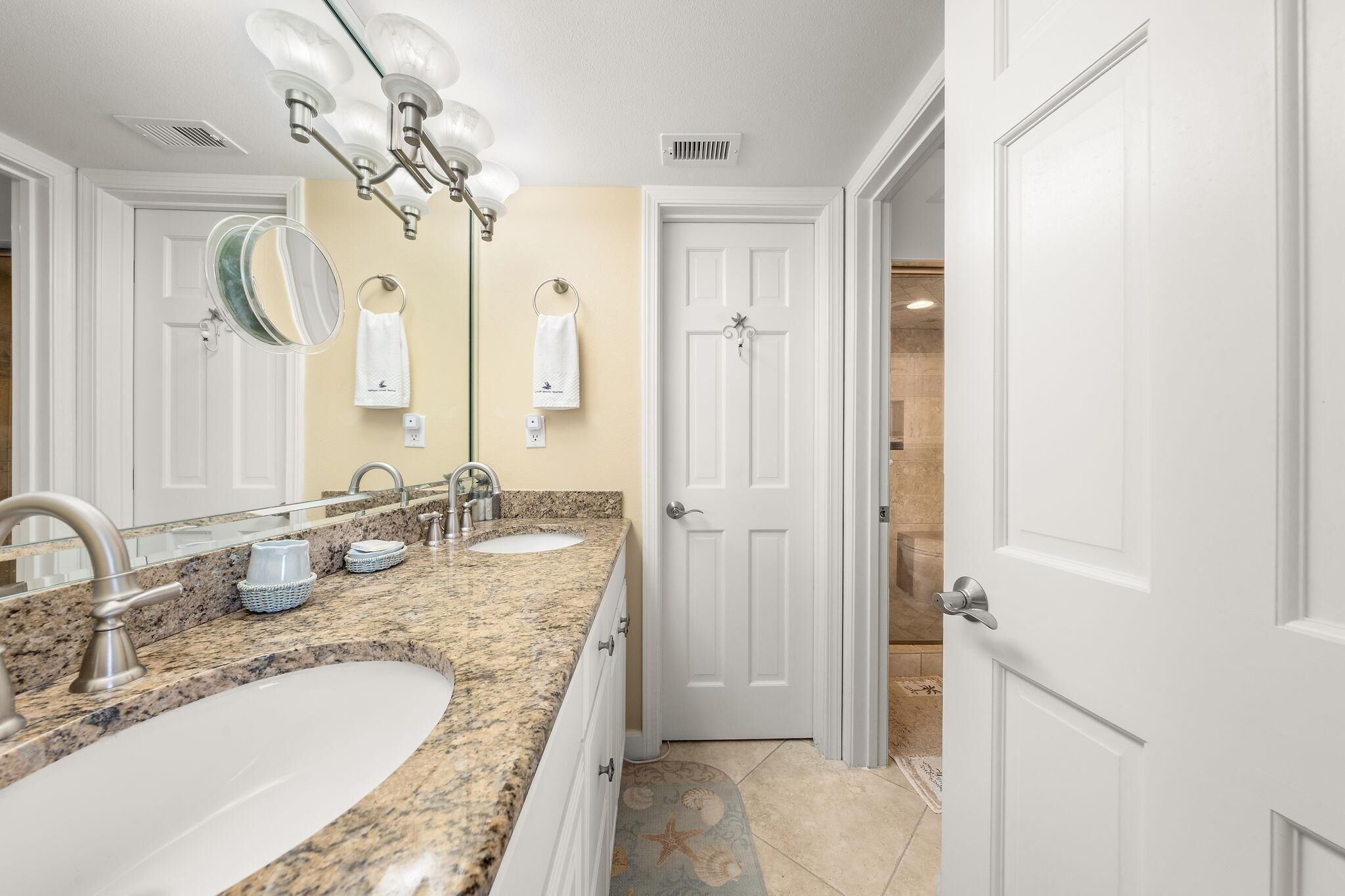 A bathroom with two sinks, a large mirror, and a towel rack.