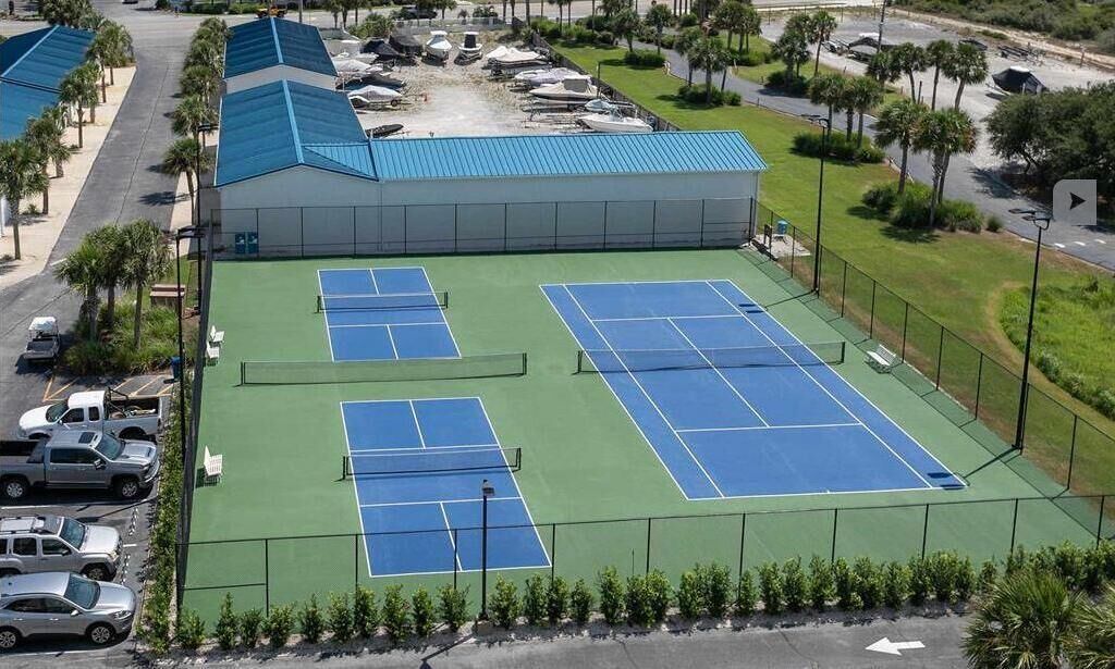 Ein Tennisplatzkomplex mit mehreren Plätzen, einem überdachten Gebäude und einem Parkbereich.