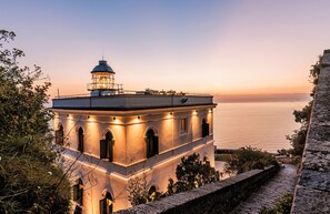 A historic building with a lighthouse on top, overlooking a calm sea. - Faro Punta Imperatore (Forio)